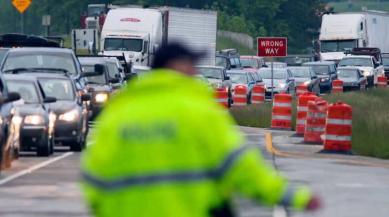 May 7, 2013 Gwinnett County : Lawrenceville police direct traffic at the scene of the jammed up intersection Tuesday morning, May 7, 2013. The westbound lanes of Ga. 316 in Gwinnett County reopened, some two hours after a logging truck overturned and shut down the major thoroughfare. According to the state Department of Transportation, two trucks and a smaller vehicle crashed just before 6 a.m. at the junction of Ga. 316 and Ga. 20 near Lawrenceville. One of the trucks overturned, losing its load of logs, the DOT said. Three people were injured, according to authorities. Gwinnett fire Lt. Colin Rhoden said that when firefighters arrived, they began treating those injured, and putting down material to absorb hydraulic fuel that was leaking from one of the vehicles. Rhoden said crews were able to absorb the hydraulic fuel before it could get into storm drains. Rhoden did not know the extent of the injuries. All lanes of Ga. 316 in both directions were blocked, as was Ga. 20. The eastbound lanes of Ga. 316 had reopened by 7 a.m., and the westbound lanes were reopened about an hour later, but traffic was still slow through the intersection as crews worked to remove the remaining wreckage. JOHN SPINK / JSPINK@AJC.COM