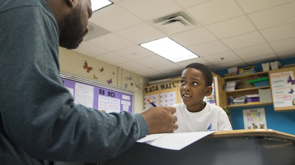 02/26/2020 — Atlanta, Georgia — Harper-Archer Elementary School third grader Dwaune Williams (right) looks to his teacher, Tony Mims (left), for assistance on pronouncing a word during class at Harper-Archer Elementary School in Atlanta, Wednesday, February 26, 2020. (ALYSSA POINTER/ALYSSA.POINTER@AJC.COM)