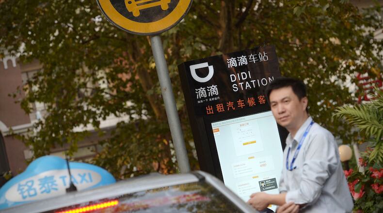 In this Thursday, Oct. 15, 2015 photo, a taxi driver waits at a newly-installed Didi Station, a road-side stop for taxis booked by the Chinese car-hailing app Didi Kuaidi, which has since changed its name to Didi Chuxing, in Shanghai. Didi Chuxing announced Friday, May 13, 2016, that Apple has invested $1 billion in the company and will become a strategic investor alongside Chinese e-commerce giant Alibaba Group and Tencent Holdings Ltd., an online games and entertainment service. (Chinatopix via AP) CHINA OUT