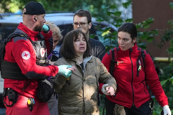 Medical workers help a woman in a yard of an apartment building destroyed after a Russian attack in Kyiv, Ukraine, early Monday, June 23, 2025. (AP Photo/Efrem Lukatsky)