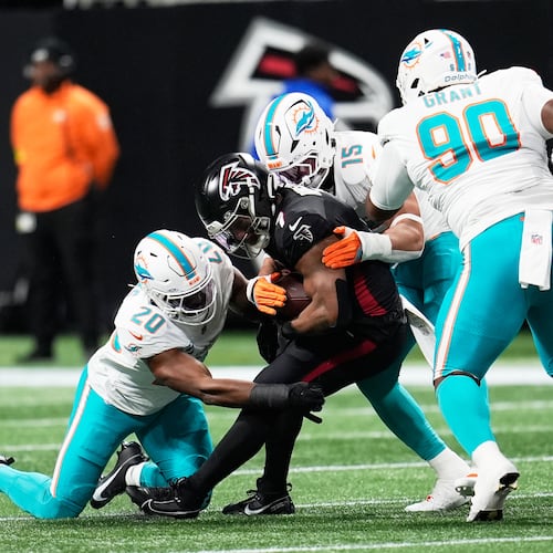Miami Dolphins linebacker Jordyn Brooks (20) and linebacker Jaelan Phillips (15) defend Atlanta Falcons running back Bijan Robinson, center, during the first half of an NFL football game, Sunday, Oct. 26, 2025, in Atlanta. (AP Photo/Mike Stewart)