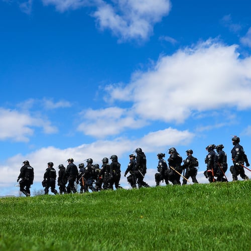 Law enforcement in riot gear walk in a field after animal welfare activists attempted to gain entry to Ridglan Farms beagle breeding and research facility on Saturday, April 18, 2026, in Blue Mounds, Wis. (Owen Ziliak/Wisconsin State Journal via AP)
