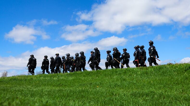 Law enforcement in riot gear walk in a field after animal welfare activists attempted to gain entry to Ridglan Farms beagle breeding and research facility on Saturday, April 18, 2026, in Blue Mounds, Wis. (Owen Ziliak/Wisconsin State Journal via AP)