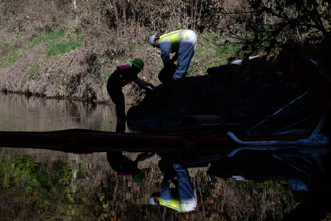 Workers clean oil and sludge runoff from the UPS plane crash from a waterway known as Northern Ditch on Nov. 8, 2025, in Louisville, Kentucky. (Jon Cherry/AP)