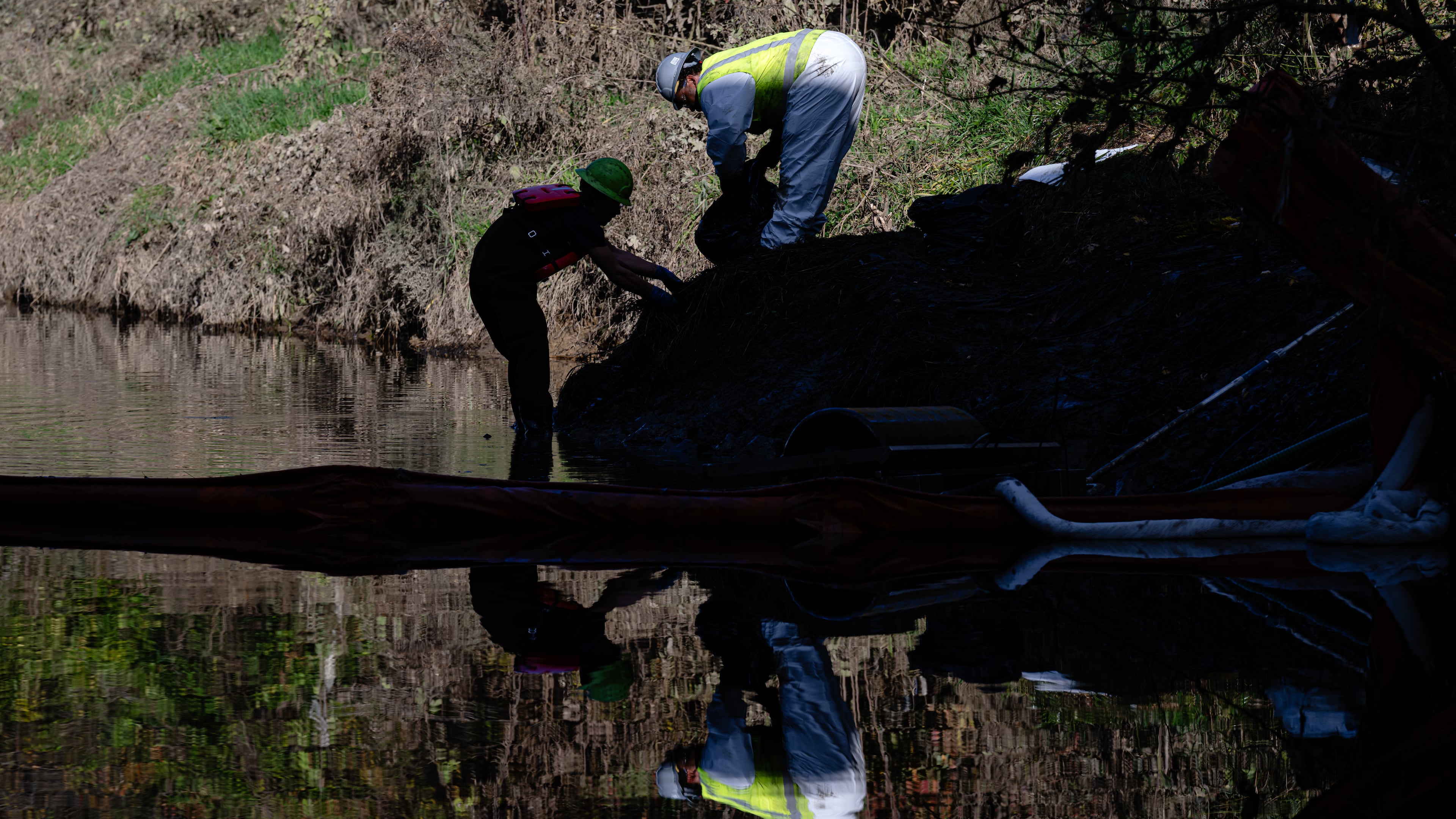 Workers clean oil and sludge runoff from the UPS plane crash from a waterway known as Northern Ditch on Nov. 8, 2025, in Louisville, Kentucky. (Jon Cherry/AP)