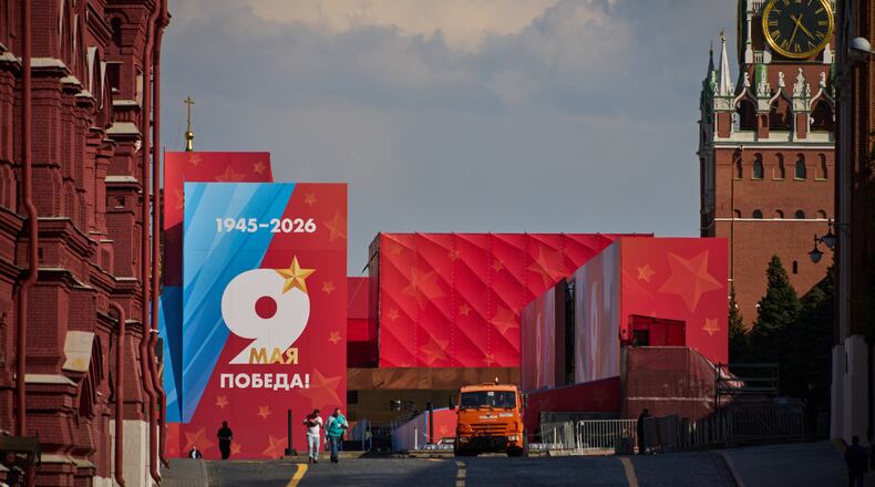 People walk in front of Victory Day poster walking from closed for entry Red Square decorated for the celebrations of the 81st anniversary of the Soviet Union's victory over Nazi Germany during World War II, in Moscow, on Wednesday, May 6, 2026, backdropped by the Spasskaya Tower on the right. (AP Photo/Alexander Zemlianichenko)