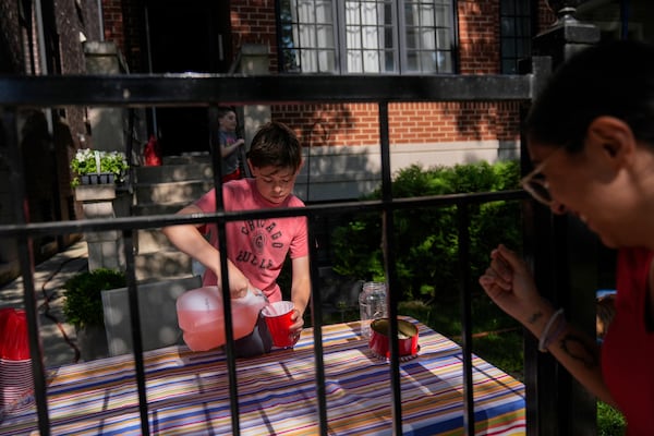 Robby, 12, who did not want to give his last name, sells lemonade in his front yard on a hot Friday, June 20, 2025, in Chicago. (AP Photo/Erin Hooley)
