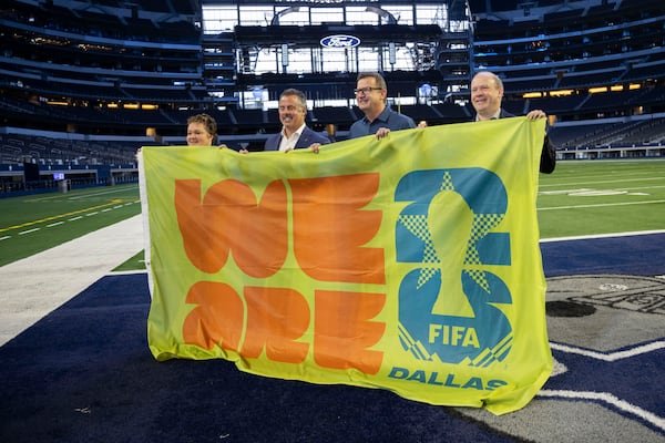 Monica Paul (from left), executive director of the Dallas Sports Commission, Chad Estes, executive vice president of business operations for the Dallas Cowboys, Heimo Schirgi, chief operating officer of World Cup, FIFA, and Dan Hunt, president of FC Dallas, hold a banner following a news conference about updates on the bid to host 2026 World Cup matches at AT&T Stadium in Arlington, Texas. (Juan Figueroa/The Dallas Morning News/TNS)