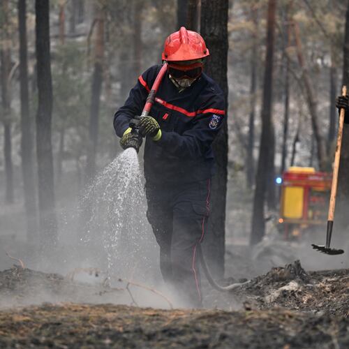 A firefighter sprays water after a wildfire in the region of the Fontainebleau forest, south of Paris, France, Tuesday, July 14, 2026. (AP Photo/Emma Da Silva)