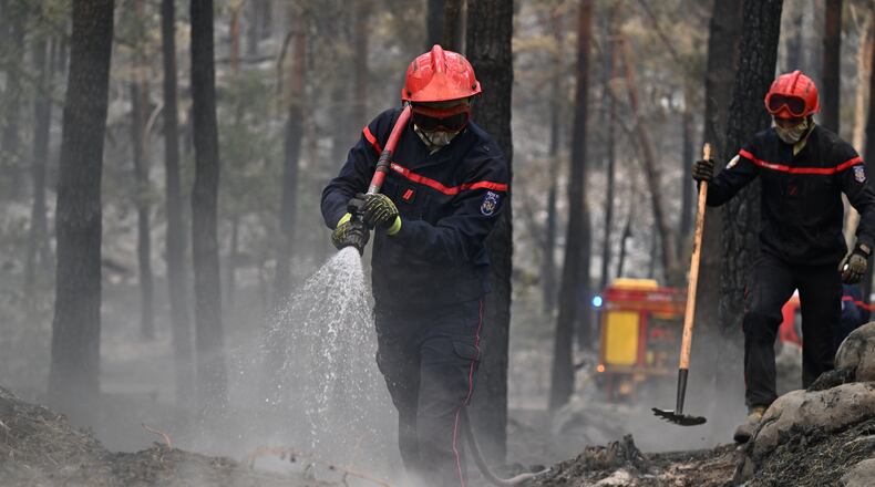 A firefighter sprays water after a wildfire in the region of the Fontainebleau forest, south of Paris, France, Tuesday, July 14, 2026. (AP Photo/Emma Da Silva)