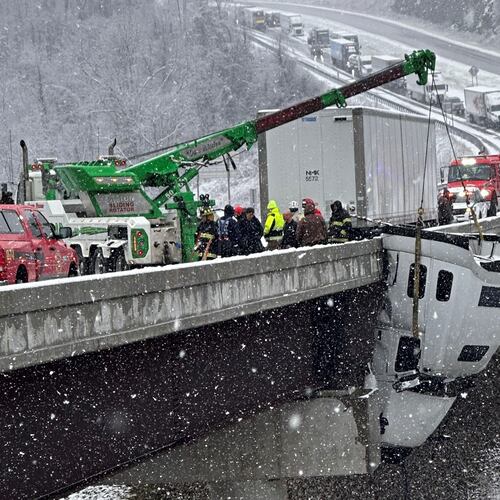 This photo provided by Vickie Flora shows crews working to remove a truck cab dangling from a bridge along U.S. Route 35 after it crashed in icy conditions Tuesday, Dec. 2, 2025, in Southside, W.Va. (Vickie Flora via AP)