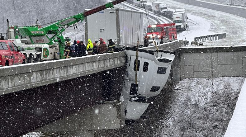 This photo provided by Vickie Flora shows crews working to remove a truck cab dangling from a bridge along U.S. Route 35 after it crashed in icy conditions Tuesday, Dec. 2, 2025, in Southside, W.Va. (Vickie Flora via AP)