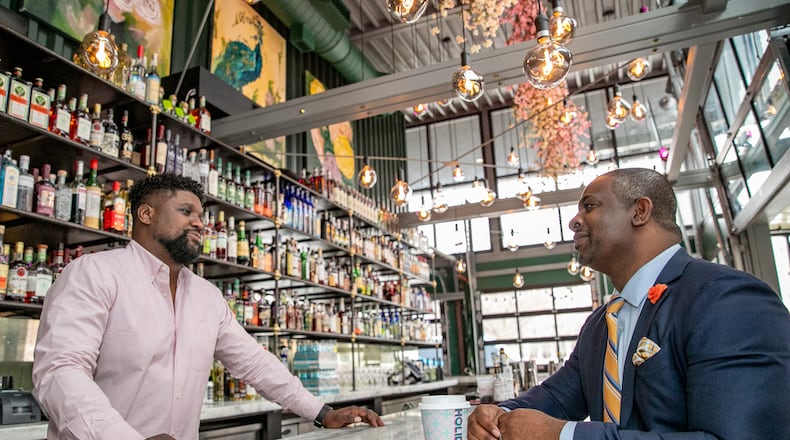 Investor Armond Davis, right, managing partner of The Paragon Group, and "A Seat at The Table Capital" owner Camaran Burke, left, catch up at Holiday Bar in West Midtown, one of Burke's four bars in Atlanta, on Wednesday, March 9, 2022. Davis is an investor working with black-owned businesses to fill the gap many African Americans face when seeking financing. Holiday Bar at Howell Mill and 14th offers coffee, cocktails and great patio space. (Jenni Girtman for The Atlanta Journal-Constitution)