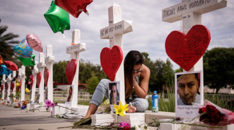 A woman writes a note on a cross at a memorial outside the Orlando Regional Medical Center on June 17, 2016. The memorial included a cross for each of the 49 victims killed in the  Pulse nightclub shooting. Not including the Pulse victims, a new report finds 2016 was the deadliest year ever for the LGBTQ community.
