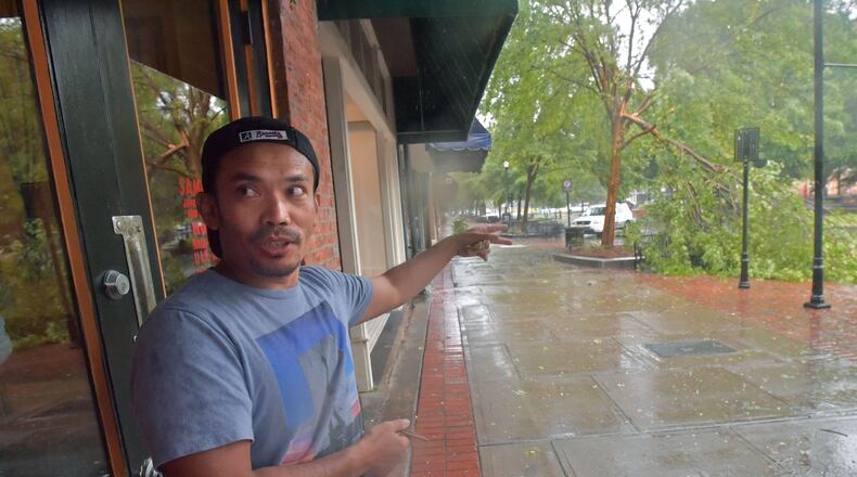 Saban Nadeak, owner of Samurai Japanese restaurant in Columbus, shows where the tree fallen onto his car on Monday. HYOSUB SHIN / HSHIN@AJC.COM