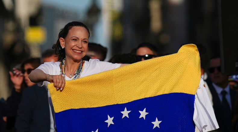 Venezuela's opposition leader Maria Corina Machado holds a Venezuelan flag on stage in front of supporters at Madrid's Puerta del Sol, in Madrid, Spain, Saturday, April 18, 2026. (AP Photo/Manu Fernandez)