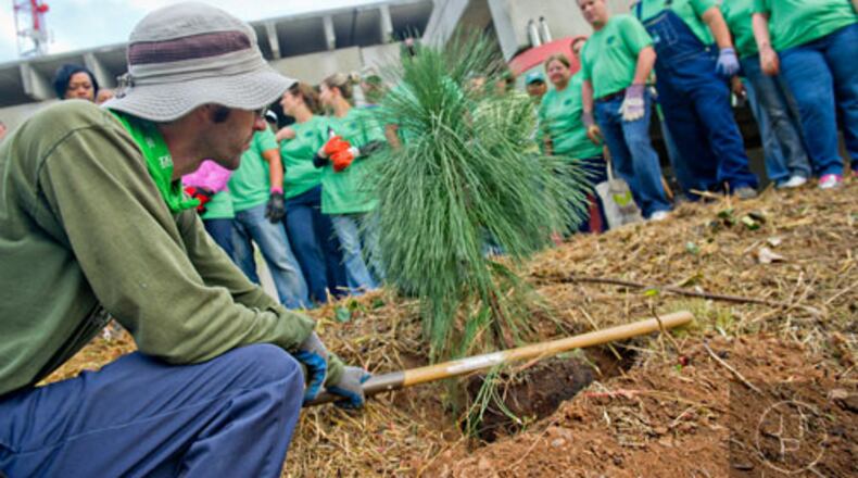 In this file photo from 2014, Brian Williams (left) demonstrates the correct way to plant a tree during an event to plant trees along the Atlanta Beltline. In 2017, Trees Atlanta will host several large Day of Service events on MLK Day. JONATHAN PHILLIPS / SPECIAL