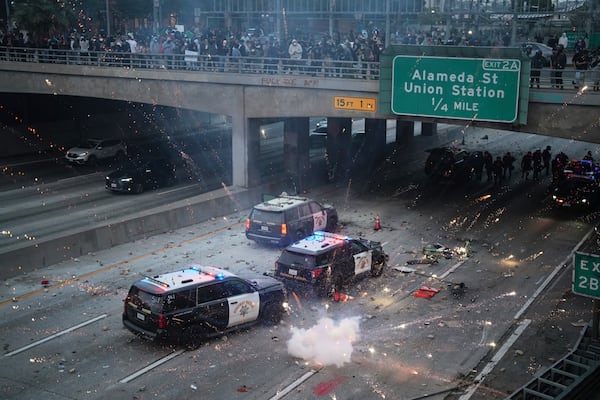 EDS NOTE: OBSCENITY A flash bomb explodes on the 101 Freeway near the metropolitan detention center of downtown Los Angeles, Sunday, June 8, 2025, following last night's immigration raid protest. (AP Photo/Eric Thayer)