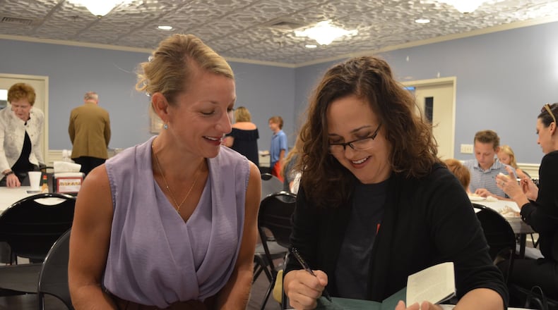 Sarah Stanley Fallaw of Marietta signs a copy of “The Next Millionaire Next Door” for a fan. Fallaw is the daughter of the late best-selling author Thomas J. Stanley. CONTRIBUTED