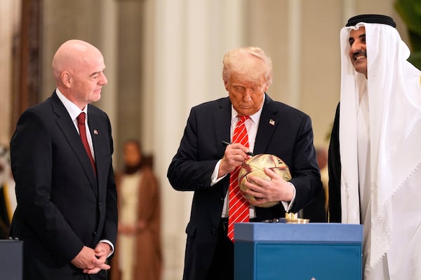 President Donald Trump signs a FIFA soccer ball as Qatar's Emir Sheikh Tamim bin Hamad Al Thani and FIFA President Gianni Infantino looks on at the Lusail Palace, Wednesday, May 14, 2025, in Doha, Qatar. (AP Photo/Alex Brandon)
