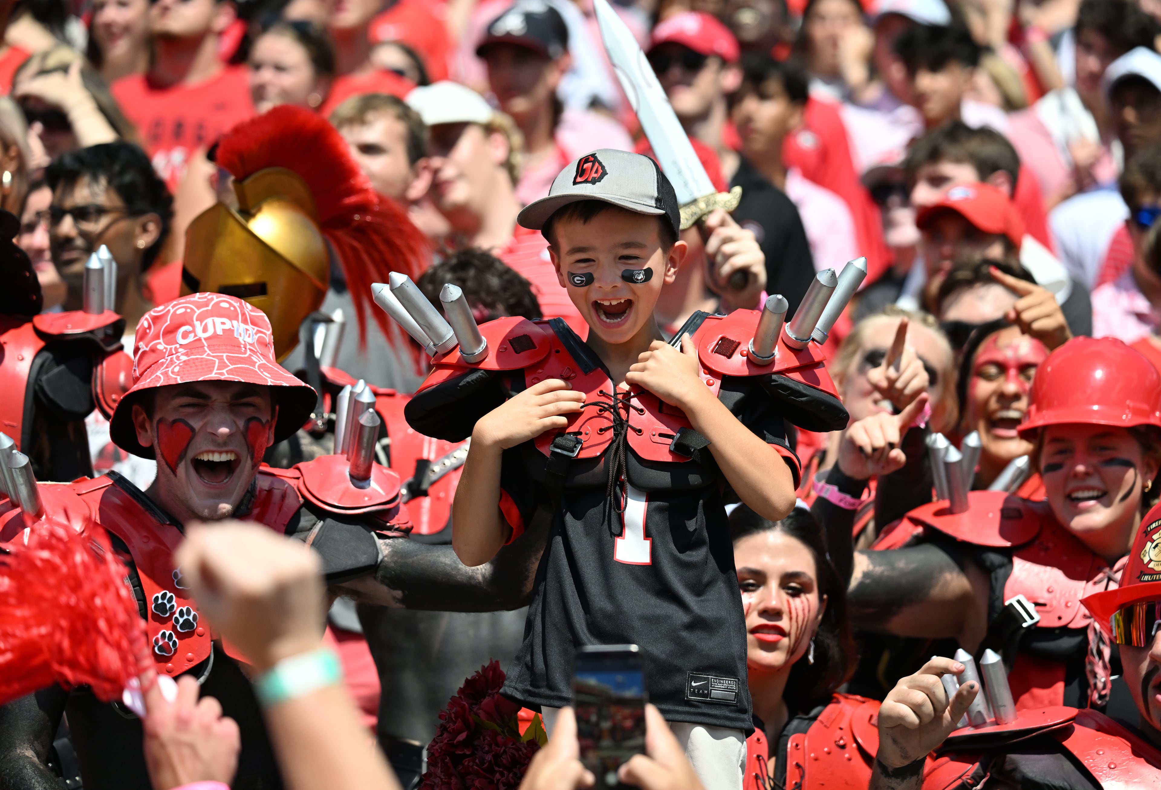 An young fan cheers among members of the Spike Squad before Georgia football's season opener and home opener against Marshall at Sanford Stadium, Saturday, August 30, 2025, in Athens. (Hyosub Shin / AJC)