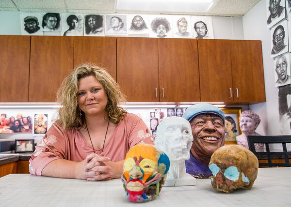 Kelly Lawson is the Georgia Bureau of Investigation's forensic artist Wednesday, July 21, 2021, and the go-to law-enforcement professional in the state when investigators need visual renderings of skulls found in the field or sketches, created with witness input, to identify criminals.  Her decade of experience and her mother’s experience in the field has produced impressive results.  As part of her training a decade ago, Lawson made the colorful skull in the foreground as muscle structure is key to her skill set.  (Jenni Girtman for The Atlanta Journal-Constitution)