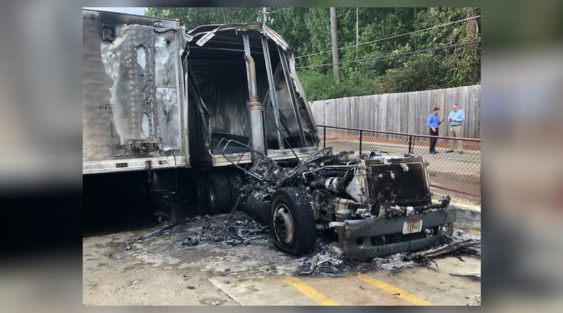 A charred Coca-Cola delivery truck sits outside a Publix after crews extinguished flames behind a DeKalb County shopping center.
