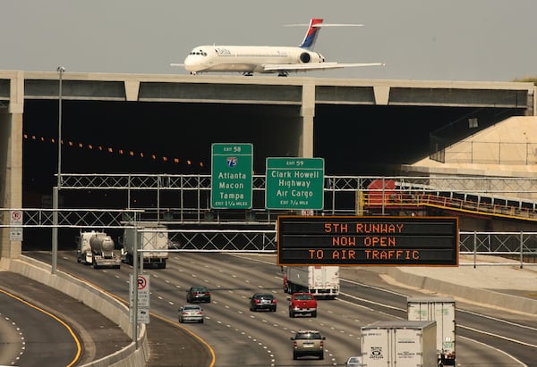 060527 - RIVERDALE, GA: A Delta plane rolls over the 5th runway bridge as cars continue to move on Interstate 285 on Saturday, 5/27/06. Today was the first day of runway was open to air traffic .PHOTO BY JOHNNY CRAWFORD/AJC STAFF