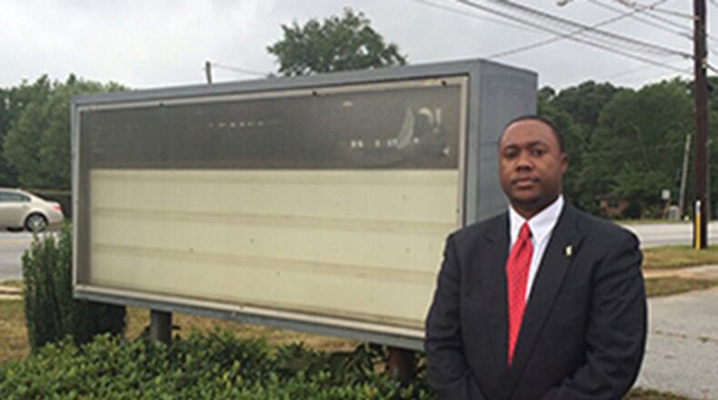 Utopian Academy Executive Director Artesius Miller stands in front of bare sign that is the center of school’s dispute with city of Riverdale.
