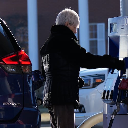 A woman checks gas prices before she fills up her vehicle's gas tank at a gas station in Buffalo Grove, Ill., Wednesday, Jan. 7, 2026. (AP Photo/Nam Y. Huh)