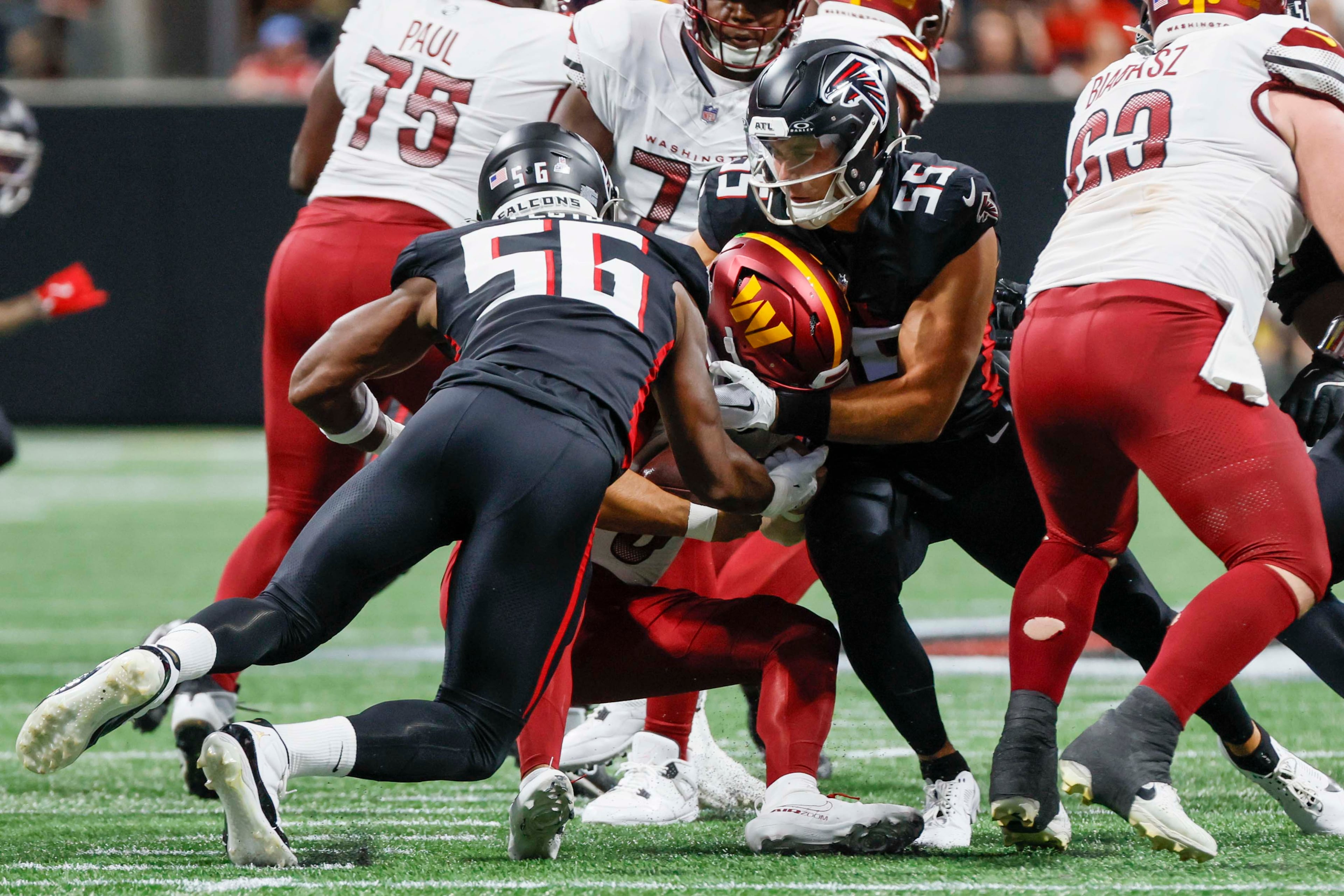 Washington Commanders quarterback Marcus Mariota is sacked by Atlanta Falcons linebacker Kaden Elliss (right) and Falcons defensive end Leonard Floyd (left) during the second half of an NFL game at Mercedes-Benz Stadium in Atlanta on Sunday, September 28, 2025.(Miguel Martinez/AJC)