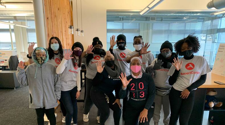 A group of 10 young people pose, wearing masks and waving at the camera for a Hands On event.