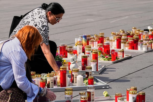 People light candles on the main square after a former student opened fire the day before at a school fatally wounding several people and injuring many others before taking his own life, Graz, Austria, Wednesday, June 11, 2025. (AP Photo/Darko Bandic)