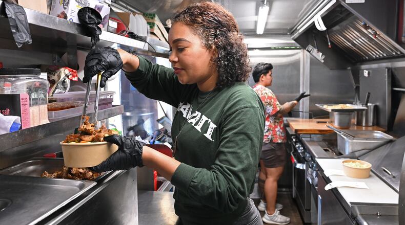 Jess Gorsuch (left) and Sara Siv, owners of Hapa Kitchen, prepare orders inside their food truck at Block & Drum in Chamblee on Wednesday, June 17, 2026. (Hyosub Shin/AJC)