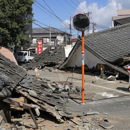 A person walks past the houses collapsed in an earthquake in Yatsushiro, Kumamoto Prefecture, southern Japan, Friday, July 31, 2026. (Koji Harada/Kyodo News via AP)