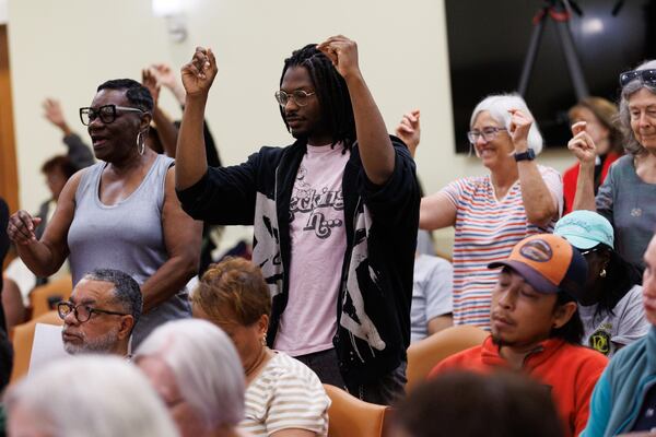 Jordan Moses and other residents snap their fingers in response to comments made by the public during a DeKalb County committee meeting that included discussion about data centers on Tuesday at the Lou Walker Senior Center in Stonecrest. (Estela Muñoz/AJC)