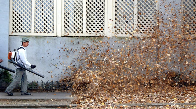 Esbin Cabrera blows leaves down 14th Street near Colony Park in Atlanta, where he and his crew from Russell Landscape Group Inc. were working. (JOHN SPINK / 2002 AJC FILE)