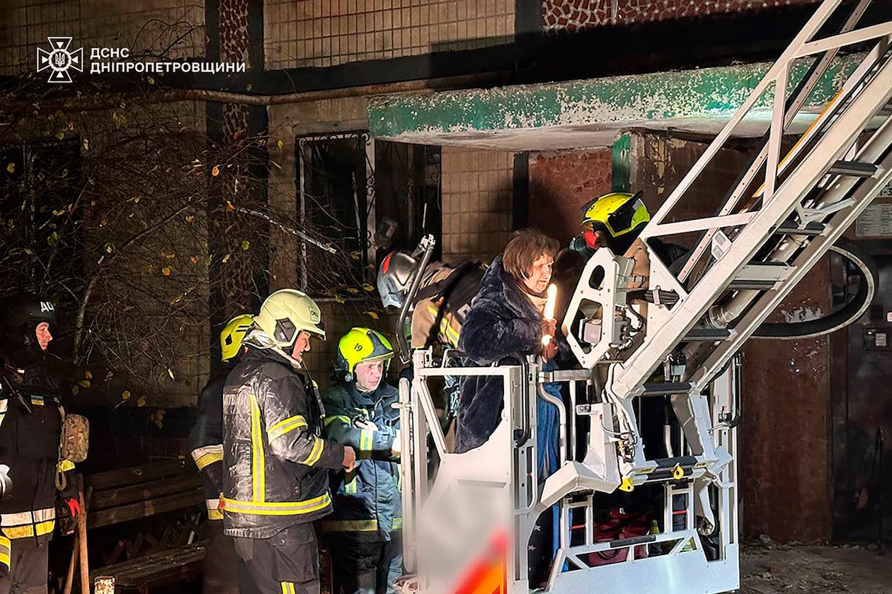 In this photo provided by the Ukrainian Emergency Service, firefighters evacuate a resident following a Russian rocket attack that hit a multi-storey apartment building in Dnipro, Ukraine, Saturday, Nov. 8, 2025. (Ukrainian Emergency Service via AP)