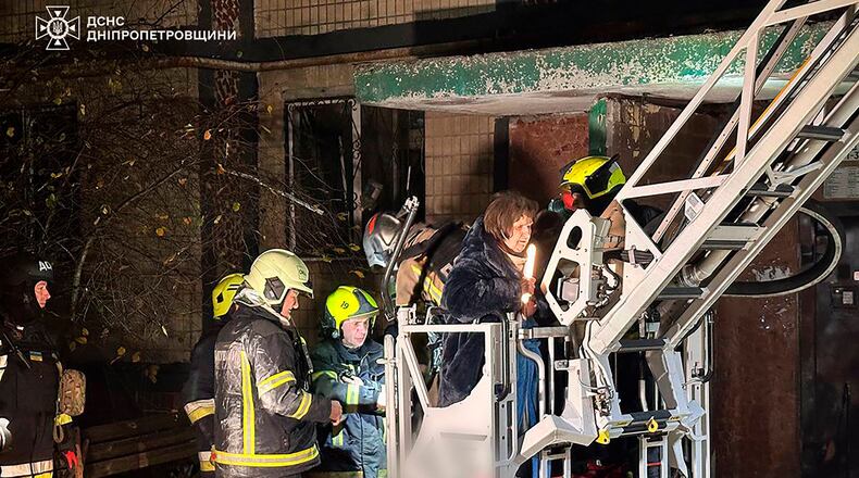 In this photo provided by the Ukrainian Emergency Service, firefighters evacuate a resident following a Russian rocket attack that hit a multi-storey apartment building in Dnipro, Ukraine, Saturday, Nov. 8, 2025. (Ukrainian Emergency Service via AP)