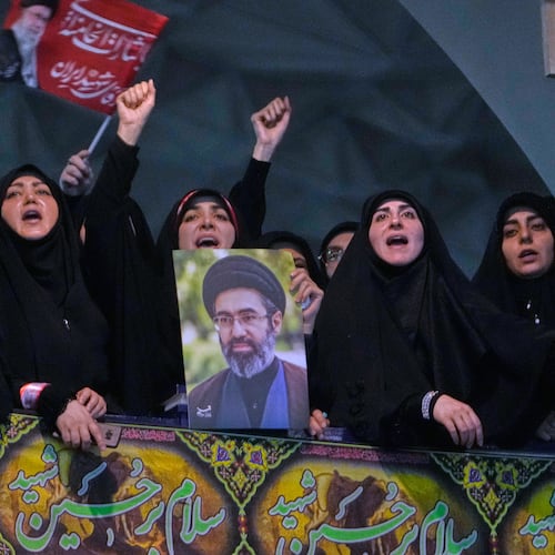 Mourners chant slogan as one of them holds a poster of the Supreme Leader Ayatollah Mojtaba Khamenei in a ceremony commemorating the late Supreme Leader Ayatollah Ali Khamenei at the Imam Khomeini Mosalla Grand Mosque in Tehran, Tuesday, July 14, 2026. (AP Photo/Vahid Salemi)