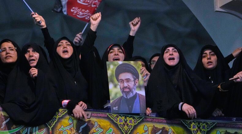 Mourners chant slogan as one of them holds a poster of the Supreme Leader Ayatollah Mojtaba Khamenei in a ceremony commemorating the late Supreme Leader Ayatollah Ali Khamenei at the Imam Khomeini Mosalla Grand Mosque in Tehran, Tuesday, July 14, 2026. (AP Photo/Vahid Salemi)
