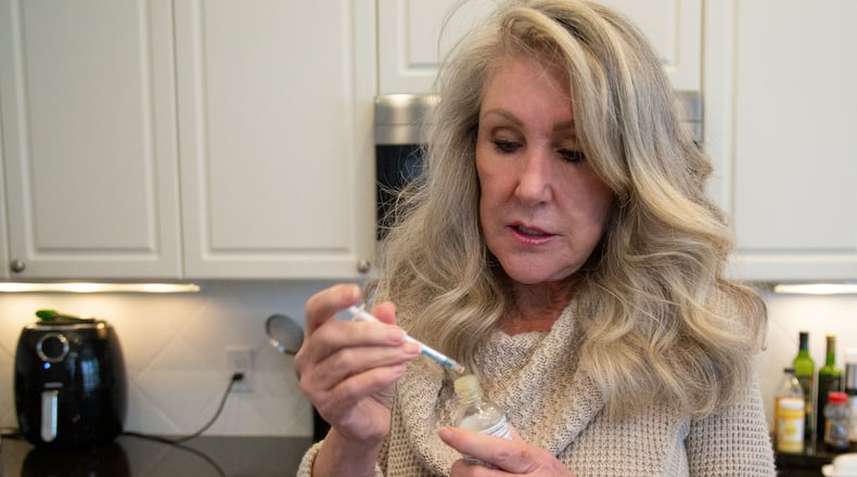 Cindy Dawson prepares her morning dose of low THC oil in the kitchen of her Smyrna home in December 2019. The Georgia Access to Medical Cannabis Commission on Wednesday unanimously approved licenses for two companies authorizing them to grow, manufacture and sell marijuana oil in Georgia within the year. STEVE SCHAEFER / SPECIAL TO THE AJC