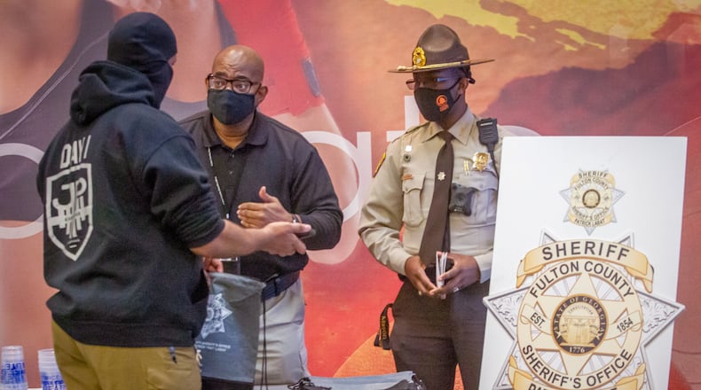 Tommy White (C) and Detention officer Rayshaun Clark talk with Robert Richardson at a Fulton County Sheriff's Office job fair at LA Fitness in Atlanta Friday, February 11, 2022.   STEVE SCHAEFER FOR THE ATLANTA JOURNAL-CONSTITUTION
