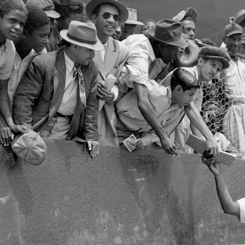 FILE - Jackie Robinson, first baseman of the Brooklyn Dodgers, returns an autograph book to a fan in the stands, during the Dodgers' spring training in Ciudad Trujillo, now Santo Domingo, in the Dominican Republic, on March 6, 1948. (AP Photo/File)