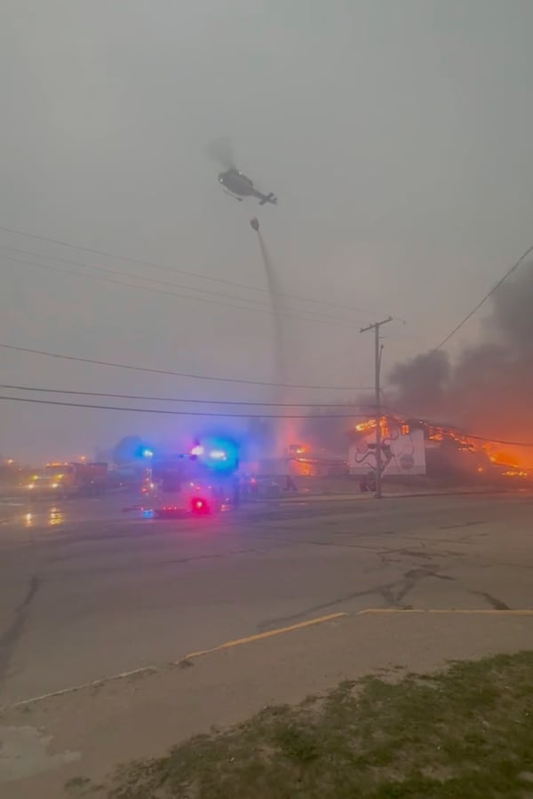 In this photo provided by Evan Bell firefighters combat the wildfires as they consumed Robertson Trading, a general store, in La Ronge, Saskatchewan on June 3, 2025. (Evan Bell via AP)