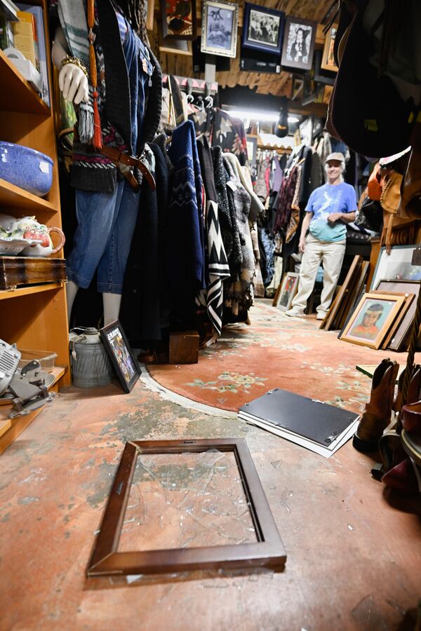 Tracy Turner, owner of the Wynola Junction, looks over pictures that fell from shelves when a earthquake hit Monday, April 14, 2025, in Julian, Calif., after an earthquake shook Southern California, sending boulders tumbling onto rural roadways outside San Diego and rattling items off shelves and walls. (AP Photo/Denis Poroy)