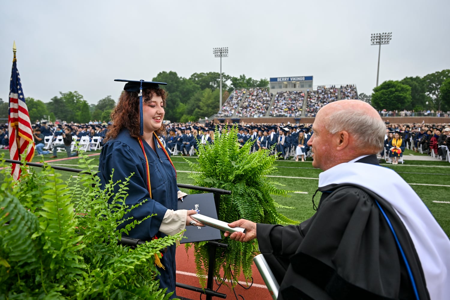 Berry College graduate Caron Bonner receives a relay baton from Dan Cathy, chairman of Chick-fil-A, during commencement on Saturday, May 9, 2026. Cathy, who served as the featured speaker, presented each graduate with a relay baton. Using the baton as part of his address, Cathy compared graduation to a relay race, reminding students that many people helped carry them to this moment and encouraging them not to "drop the baton" as they move into the next chapter of life. (Brant Sanderlin/Berry College)