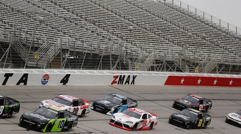 Cars drive by empty stands during a NASCAR Xfinity Series auto race at Atlanta Motor Speedway on Saturday, June 6, 2020, in Hampton, Ga. (AP Photo/Brynn Anderson)