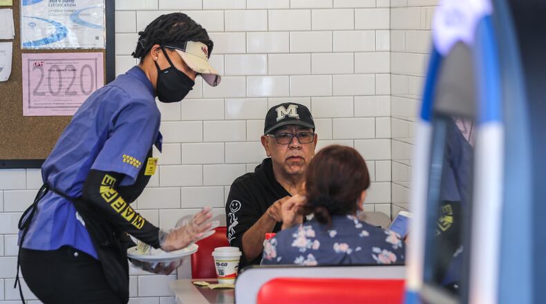 April 27, 2020 Brookhaven: Waffle House's Miss D (left) serves Daniel Bahena and his guest (right) on Monday, April 27, 2020 at The Waffle House at 2886 Clairmont Road in Brookhaven. Restaurants around metro Atlanta began to reopen dining rooms Monday, April 27, 2020 as restrictions related to the coronavirus pandemic are lifted. Restaurants will be allowed to operate with in-person dining as long as they follow a set of 39 guidelines laid out by the state government, which include a requirement that all employees wear masks, a maximum of 10 customers per 500 square feet of floor space and a maximum of six diners per table. JOHN SPINK/JSPINK@AJC.COM
