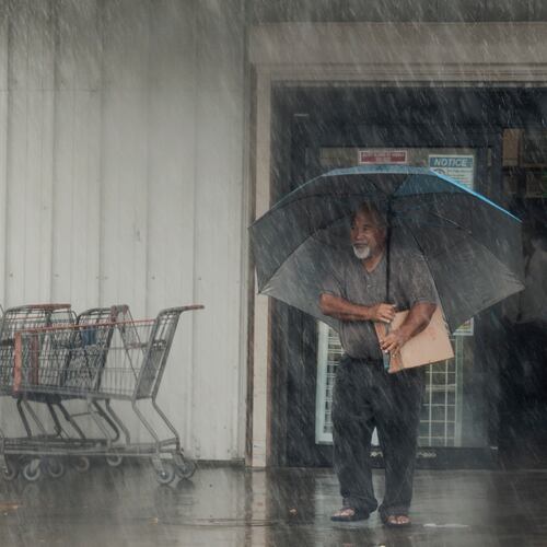 A resident carries supplies during Hurricane Lala in Hawaiian Ocean View, Hawaii, Saturday, Aug. 15, 2026. (Stephen Lam/San Francisco Chronicle via AP)